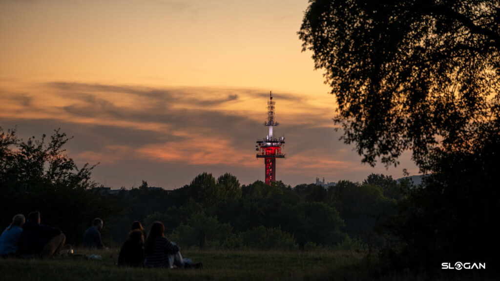Fotografia krajobrazu i architektury Kraków - ludzie na pikniku i wieża nadawcza na Krzemionkach o zachodzie słońca.