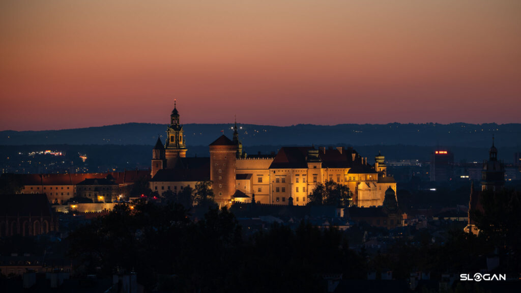 Oświetlony Zamek Królewski na Wawelu o zmierzchu widoczny z Kopca Krakusa